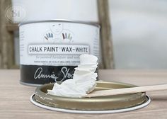 a can of chalk paint next to a wooden spoon with white whipped cream on it