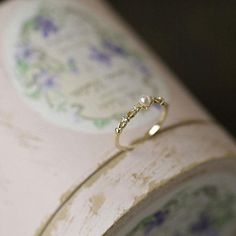 a gold ring sitting on top of a piece of white paper with purple and blue flowers