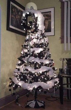 a white christmas tree decorated with black and silver ornaments