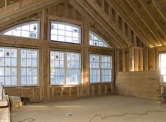 an unfinished room with large windows and wooden beams