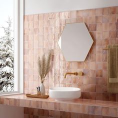 a bathroom with pink tiles and a gold faucet next to a white sink