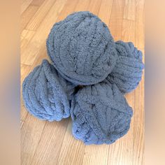 three blue balls of yarn sitting on top of a wooden floor