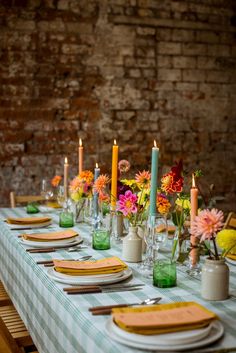 a table set with place settings and flowers in vases, candles and napkins