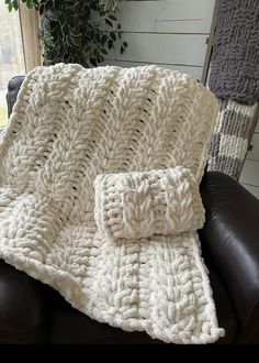 a white crocheted blanket sitting on top of a leather chair