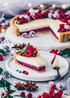 a slice of cheesecake on a plate with berries and christmas greenery around it