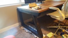 an office desk with a computer on it in front of a window and papers scattered about the floor