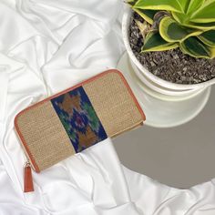 a small purse sitting on top of a white sheet next to a potted plant