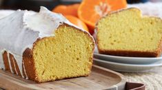 a loaf of orange pound cake with icing on a cutting board next to an orange slice