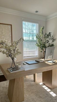 two vases with flowers are sitting on a table in front of a window,