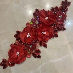 some red flowers are laying on a white marble surface with beads and sequins