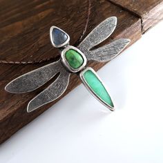 Handmade .999 fine silver dragonfly pendant with a beautiful labradorite, parrot wing chrysocolla and chrysoprase cabachons. This is a chunky and beautiful large dragonfly necklace. Pendant measures  8.8cm wide by 6.8cm long.  Pendant including stone weighs 58 grams. Includes gift box. I offer a few different cord lengths. The cord is 3mm round braided leather with sterling silver tube ends and clasp.  Handmade by Mike Summers. We are husband and wife Mike and Annie, making silver jewelry in two uniquely different styles. With a passion for rocks and gemstones, we also cut and polish our own cabochons to use in our creations. We live and work in a tiny cabin in a remote part of Talkeetna in Alaska and it's always a bit of an adventure crossing our creek in a boat to get on the roads to the Handmade Green Dragonfly Jewelry, Silver Dragonfly Necklace, Dragonfly Necklace, Leather Corded Necklace, Dragonfly Pendant, Cat Necklace, Long Pendant, Cord Necklace, Braided Leather