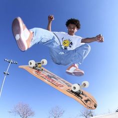 a young man flying through the air while riding a skateboard in front of a blue sky