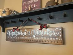 a wooden sign hanging from the side of a wall next to a shelf with christmas decorations on it