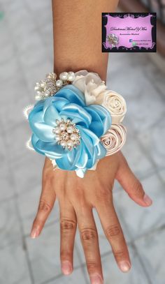 a woman's hand wearing a blue and white wrist corsage