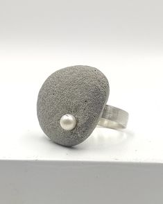 Concrete ring 925 Sterling Silver for women. A handcrafted ring made with 925 Sterling Silver and adorned with one asymmetric concrete charm, adorned with one white freshwater pearl!  A statement ring for appearances to be discussed! Freshwater pearl is June's birthstone! In contact with skin, moisture and air, concrete becomes darker. Αs each piece is individually handmade, slight variations in  texture are possible. DESCRIPTIONS and MEASUREMENTS: Material:sterling silver . Material: Concrete ,freshwater pearl. Dimensions concrete: 2,6*3,3cm 1,023*1,29 Size ring in photo: 7,5 USA size SEE MORE CONCRETE JEWELRY HERE: www.etsy.com/shop/ArtisJewels?ref=seller-platform-mcnav§ion_id=36353295 Visit my Etsy shop, ArtisJewels, to see more rings and jewelry and other unique handmade pieces. www.et Concrete Ring, Architectural Jewelry, Concrete Jewelry, Handcrafted Rings, White Freshwater Pearl, June Birth Stone, Silver Material, Silver Band, Statement Ring