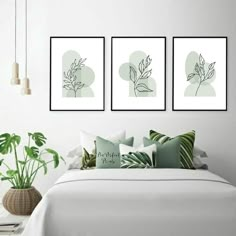 three framed art prints on the wall above a bed with pillows and plants in vases