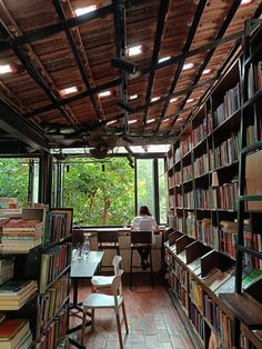 a woman sitting at a table in a library filled with books