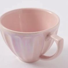 a pink coffee cup sitting on top of a white table