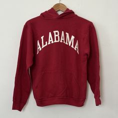 Vintage 1990's Alabama Crimson Tide Hoodie Sweatshirt sz. S in Crimson by Russell Athletic, the classic made in the USA hoodie by Russell that have become so popular because of their fit, feel, and classic vintage look.  Features crimson hoodie design, ribbed knit cuffs and waistband, 'ALABAMA' in all caps white letter screen printed across the front.  Some nice light vintage cracking to the screen printed letters.  In Good vintage condition, a few light spots on right sleeve (see video) may come out with wash, we have not tried.  Aside from that, no rips, holes, tears, or fading.  Please see and zoom all pics.  Great classic vintage Russell Alabama sweatshirt, from the 80's or early 90's when they were still made in the USA.  They don't make them with this vintage design and cut, or this Alabama Hoodie, Alabama Sweatshirt, Usa Hoodie, Printed Letters, Light Spots, Russell Athletic, Roll Tide, White Letters, Alabama Crimson