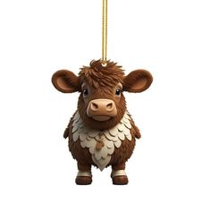 a brown and white cow ornament hanging from a gold colored chain on a white background