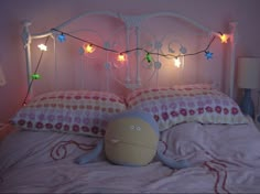 a stuffed animal sitting on top of a bed next to a night stand with lights