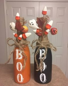 two painted pumpkins are sitting on top of the bottles that have bowling pins in them