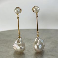 **Handmade Double Pearl Dangling Baroque Earrings** Elevate your elegance with these stunning handmade double pearl dangling baroque earrings. Featuring genuine button pearl studs, approximately 8mm in size, paired with large, lustrous, AAA quality white baroque pearls measuring around 15mm x 21mm. The baroque pearls are suspended from a long, gold-plated bar over a brass body, creating a beautiful, fluid movement with every step. The total length of these earrings from the tip of the pearl stud to the bottom of the baroque pearl is approximately 2.5 to 3 inches. These gorgeous baroque pearl earrings are the perfect accessory for weddings, bridal events, or any formal occasion. Their eye-catching design adds a touch of sophistication to any outfit, ensuring you make a lasting impression. M Luxury Long Drop Pearl Earrings For Wedding, Handmade Pear-shaped Elegant Pearl Earrings, Elegant Handmade Pear-shaped Pearl Earrings, Elegant Baroque Pearl Earrings With Pearl Charm, Long Drop Baroque Pearl Earrings For Wedding, Baroque Pearl Long Drop Wedding Jewelry, Wedding Long Drop Baroque Pearl Earrings, Formal Baroque Pearl Earrings, Baroque Pearl Long Drop Earrings