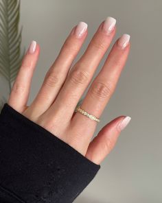 a woman's hand with white manies and a gold ring on it, next to a plant