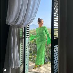 a woman in a green dress is looking out the window