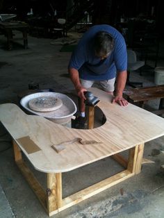 a man sanding down a wooden table with an electric sander