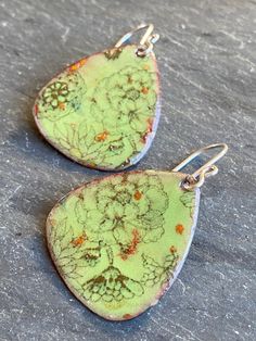 Handmade enamel copper earrings with a beautiful, delicate floral design that complement business or casual outfits. The earrings have a green background, black floral design with small color accents. Approximate measurements: Enamel Teardrop: 1 1/8" x 1" Hang length: 1 7/8" Sterling Silver Earwires. To create this pair of boho flower earrings, multiple layers of finely powdered glass are fused to copper using a torch flame to melt the glass. The floral design is added by firing a beautifully detailed decal onto the final layer of glass. We love making handmade bohemian vibe jewelry and hope you love it too! See more of our copper and enameled copper earrings and pendants here: www.etsy.com/shop/blueberrybayjewelry Hand Painted Dangle Flower Earrings, Green Nickel-free Flower Earrings, Torch Fired Enamel, Torch Fired Enamel Jewelry, Flower Earrings Dangle, Enameling Jewelry, Earrings Multiple, Copper Uses, Polymer Inspiration