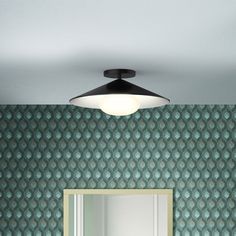 a bathroom with green wallpaper and a black light fixture over the mirror on the wall