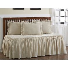 the bed is made up with ruffled linens and pillows on top of it