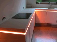 a kitchen with white cabinets and an orange light under the counter top is lit up