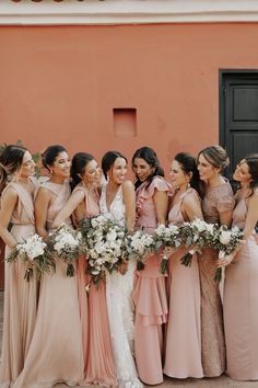 a group of women standing next to each other in front of a building with flowers