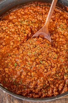 a pot filled with sauce on top of a wooden table and the words school cafeteria spaghetti and meat sauce