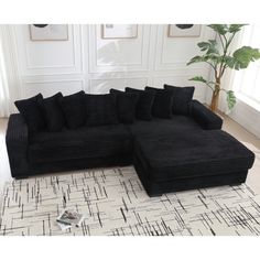 a black sectional sofa sitting on top of a rug in front of a white wall