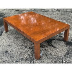 a square wooden table sitting on top of a cement floor next to a parking lot