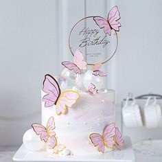 a white cake with pink butterflies on it and a happy birthday sign in the middle