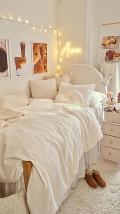 a bedroom with white bedding and lights on the wall