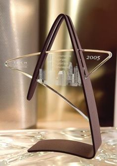 an award is displayed in front of a metallic background and silver vase with cityscape on it