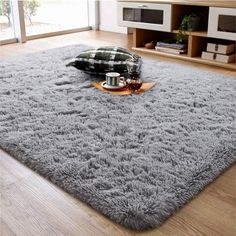 a living room area with a gray rug on the floor and a coffee cup in front of it