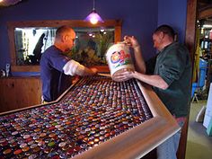 two men working on a table covered with cans