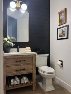 a white toilet sitting next to a wooden cabinet in a bathroom under a vanity mirror