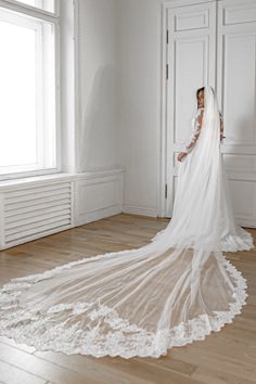 a woman in a wedding dress standing on the floor with her veil draped over her head