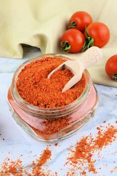 a jar filled with red stuff next to some tomatoes