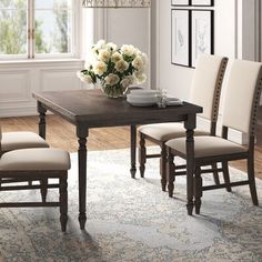 a dining table with four chairs and a vase of flowers on top of the table