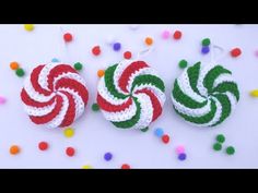 two crocheted candy canes hanging from strings on a white surface surrounded by confetti