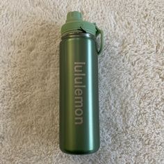 a green water bottle sitting on top of a white carpet