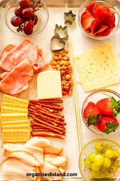 an assortment of cheeses, crackers, fruit and meats on a tray